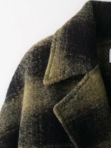 Detail of green and black plaid wool coat showing thick tweed texture and lapel