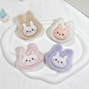 Detailed view of four colorful plush bunny charms for accessories on a white plate