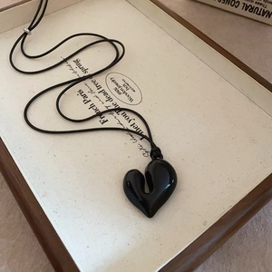 Close-up of a vintage black resin heart pendant on a rope chain for a chic retro style