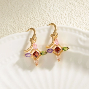 Golden clover-shaped earrings with colorful zircon gemstones displayed on a white plate