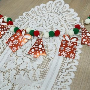 Christmas garland with pom-poms and gift box cutouts on a white lace table runner