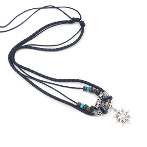Detail of vintage sun pendant necklace with multi-layer braided leather cord and colored beads