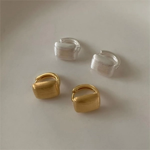 Detail of brushed gold and silver hoop earrings with a matte textured rectangular design
