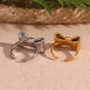 Detailed view of silver and gold bow rings on natural stone with a green leaf