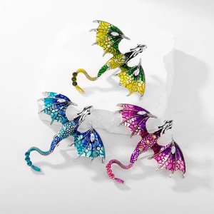 Close-up of three enamel flying dragon brooches with crystals on white stone display