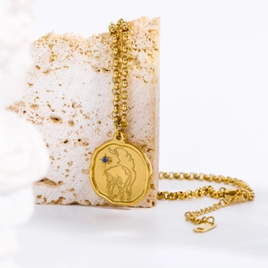 Detail of vintage Greek medallion necklace with blue stone on beige stone pedestal