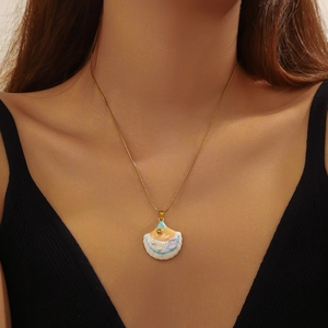 Gold shell pendant necklace with blue enamel details and white pearls on model