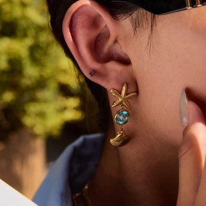 Titanium steel starfish and blue stone shell pendant earrings worn by a model