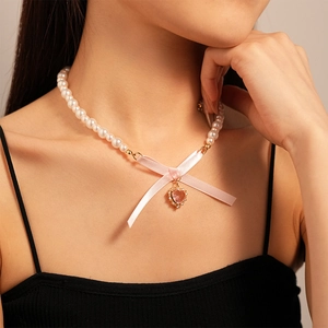 Elegant pearl necklace with pink silk bow and heart pendant on a model's collarbone