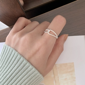 Detail shot of a minimalist 925 silver twisted rope cross ring on a thumb