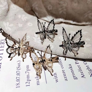 Detail of four butterfly hair clips in gold and silver metal with hollow wireframes