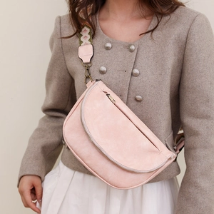 Close-up of a pink crescent crossbody bag with a bohemian geometric jacquard strap