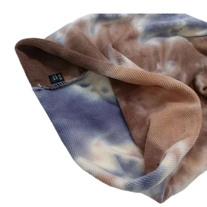Close-up of tie-dye knit hat lining showing 95% cotton fabric texture and label