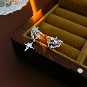 Asymmetric silver star earrings with moonstone and pavé zircons on a jewelry box