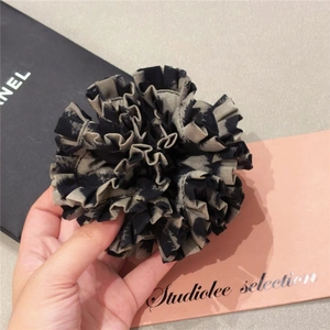 Detailed view of leopard pattern hair scrunchie with layered pleated fabric design