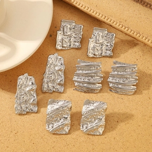 Macro detail of textured silver hammer pattern earrings with metallic fluid design