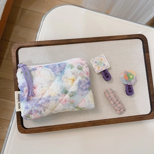 Close-up of floral quilted mini storage pouch with matching hair clips on a linen tray