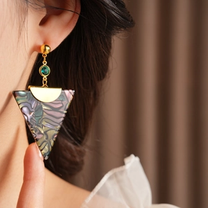 Detail of vintage gold triangle earring with green gemstone and iridescent shell inlay