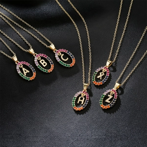 Gold plated initial necklace with rainbow zircon halo on black leather background