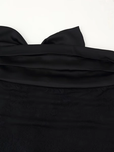 Close-up of black satin fabric with intricate lace patchwork and detailed stitching