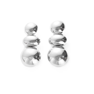 Detail of silver drop earrings featuring three polished metal spheres in vertical stack