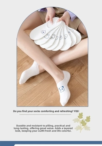 Close-up of white cotton low-cut socks with blue cartoon patterns on wooden floor