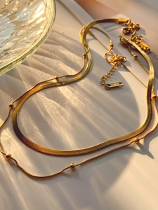 Macro shot of double-layer gold snake chain and beaded necklace with light shadow effect