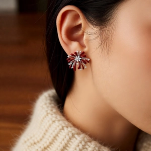 Detailed view of red floral firework stud earrings with zircon stones on female model