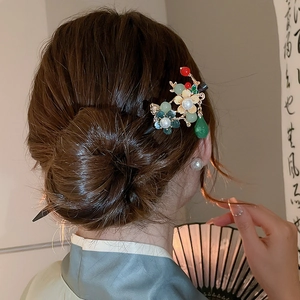 Detailed close-up of a vintage floral hairpin with pearls and green dangling charms
