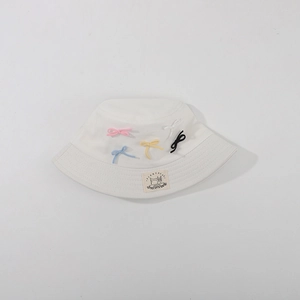 Close-up of white sun hat featuring colorful bows and a vintage fabric brand label