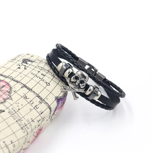 Detail of black woven leather bracelet with metal skull and crossbones on vintage box