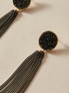 Detail of vintage long black tassel earrings with golden stud and metallic chains