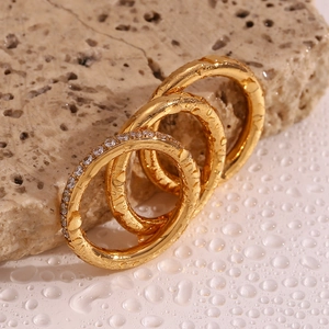 Close-up of three 18K gold plated stainless steel rings with zircon on wet stone background