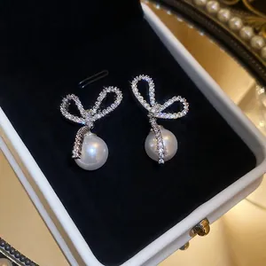Elegant bow-shaped earrings with sparkling cubic zirconia and white hanging pearls