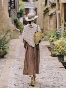 Outdoor street style view of beige knitted triangular shawl paired with a vintage dress