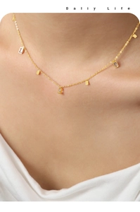 Detailed view of titanium steel gold necklace with square zircon charms on model