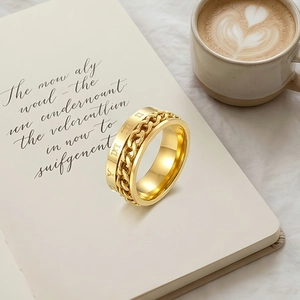 Détail de bague en acier doré avec chiffres romains posée sur un carnet beige élégant