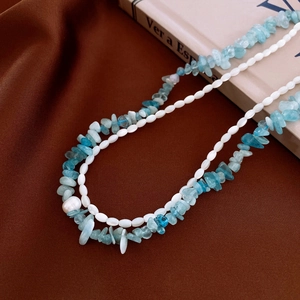 Makro-Detail eines zweilagigen Armbands mit hellblauen Steinen und weißen Perlen auf Leder
