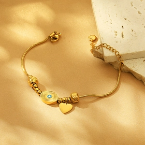Detailed view of a gold snake chain necklace with heart and blue evil eye charms