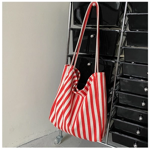 Vertical red and white striped canvas tote bag hanging on a modern industrial metal rack
