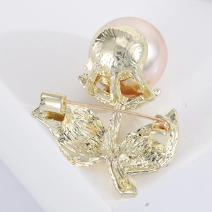 Macro shot of gold floral brooch with large pink imitation pearl and pin backing