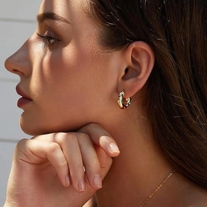 Detail of vintage gold hoop earrings with colorful gemstones worn on a model ear
