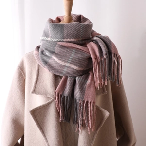 Detail of pink and gray plaid scarf with soft tassels on a mannequin with beige coat