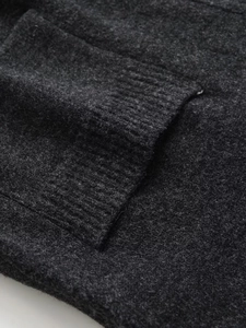 Detail of dark charcoal knit vest showing high-quality wool texture and ribbed pocket hem