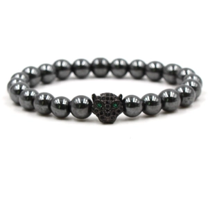 Macro detail of natural stone beaded bracelet featuring a black leopard head with green eyes
