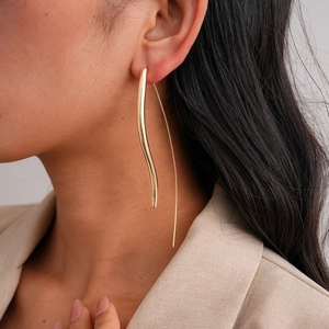 Close-up of model wearing 18K gold plated long wavy drop earrings with high polish finish