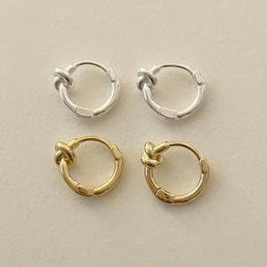 Detail showing gold and silver S925 sterling silver knot hoop earrings on beige background