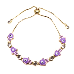 Detail of purple enamel Hamsa Hand charms and cubic zirconia on gold adjustable bracelet