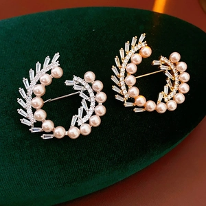 Macro shot of gold and silver flower wreath brooches with pearls and zircons on velvet