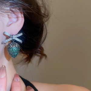 Primo piano di una modella con orecchini a fiocco d'argento e fragola verde con zirconi